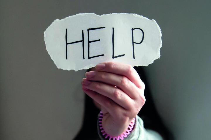 Frau hält Schild mit der Aufschrift "Help" in die Höhe